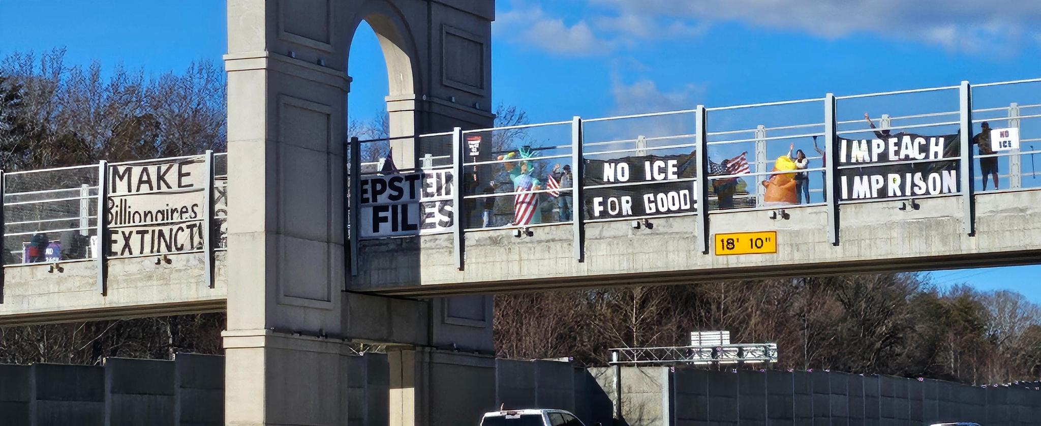Banners along the overpass railing reading make billionaires extinct, Epstein files, no ICE for good, impeach imprison